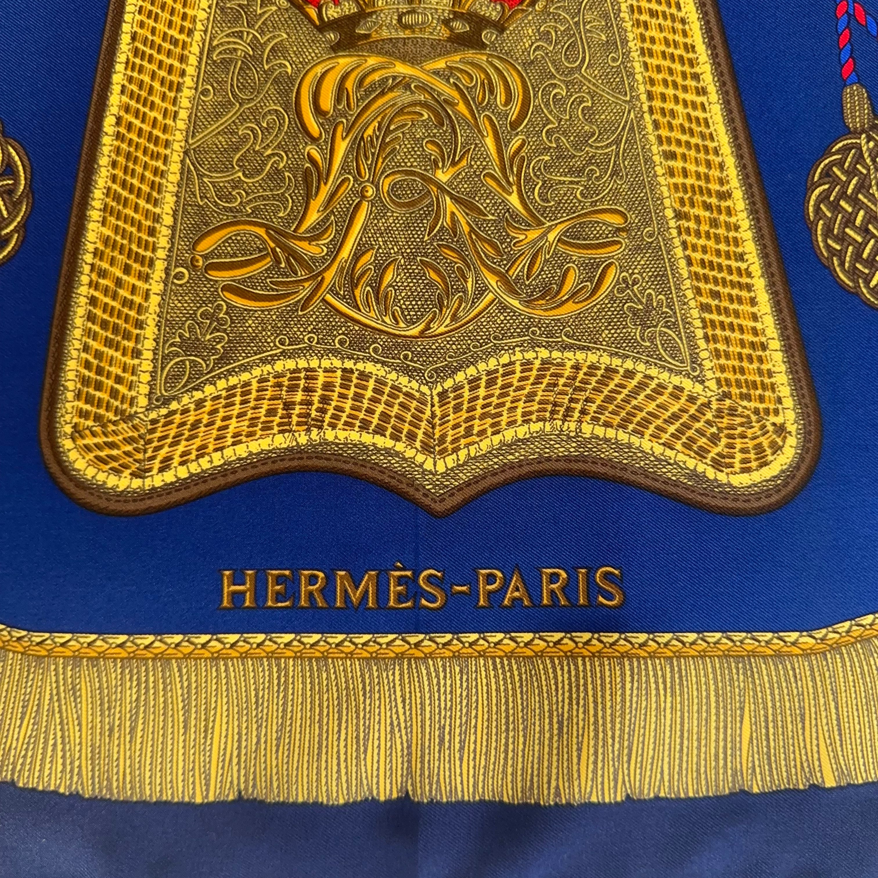 Détail du bas du foulard : sabretache dorée brodée et signature "HERMÈS - PARIS" en lettres d'or sur fond bleu roi.