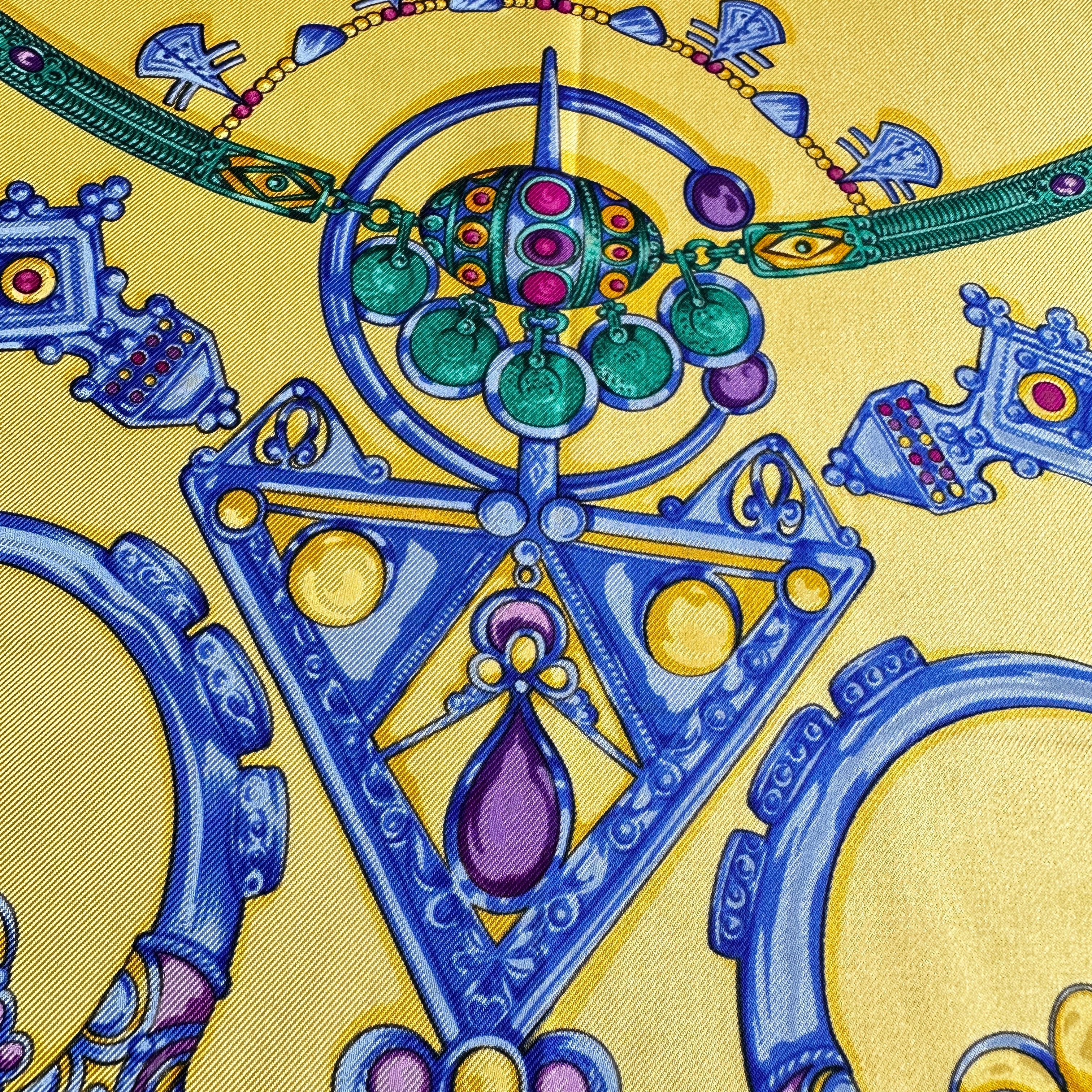 Gros plan sur un pendentif triangulaire vert de style touareg sur soie violette.