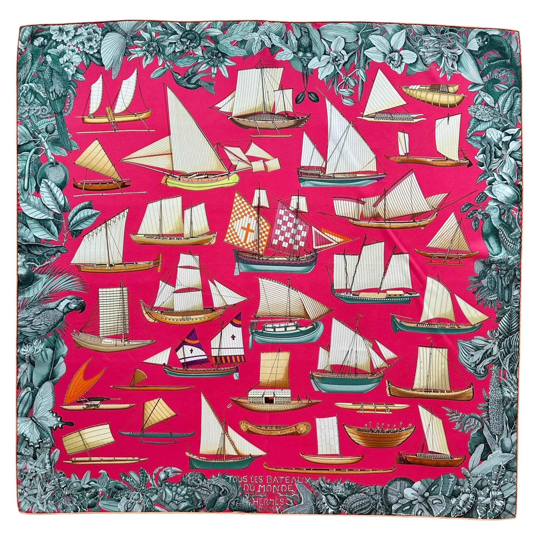 Vue générale du foulard Hermès intitulé Tous les Bateaux du Monde représentant les embarcations de différents pays sur un fond rose shocking bordé par une frise gris bleuté