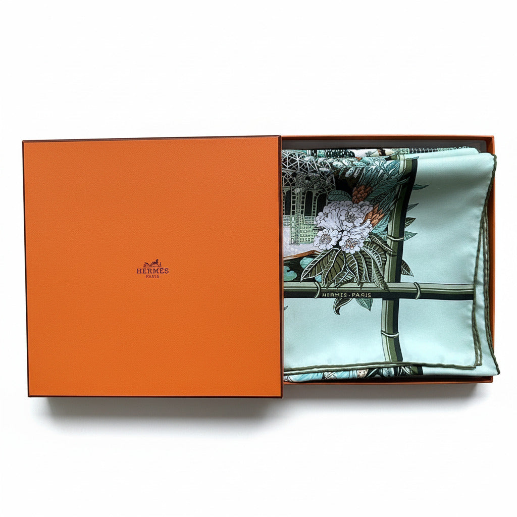 Foulard Hermès Jardin d'Hiver d'Annie Faivre plié avec sa boîte orange officielle Hermès.