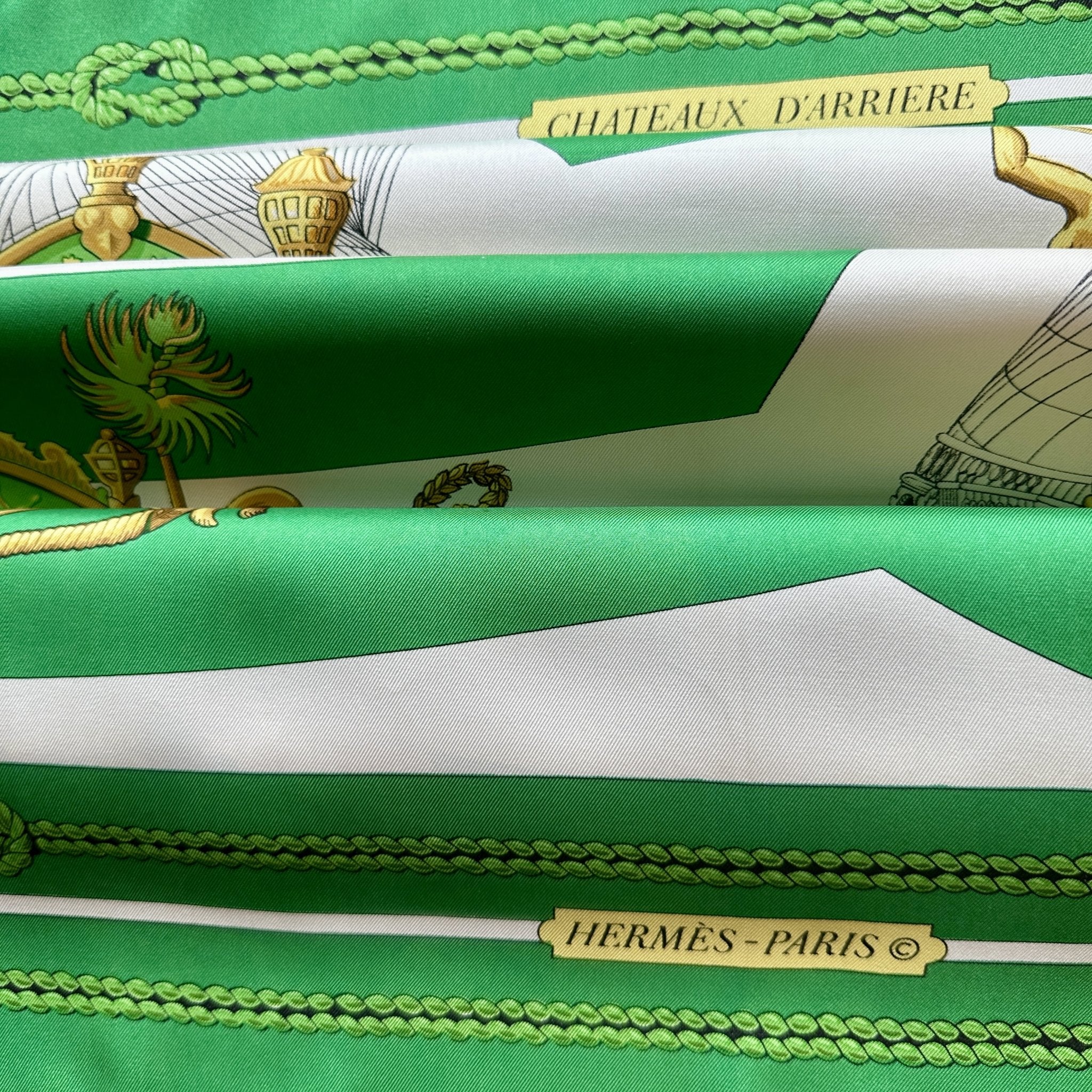 Vue du foulard Hermès vert blanc et or  intitulé Chateaux d'arrière et présenté avec un effet plissé